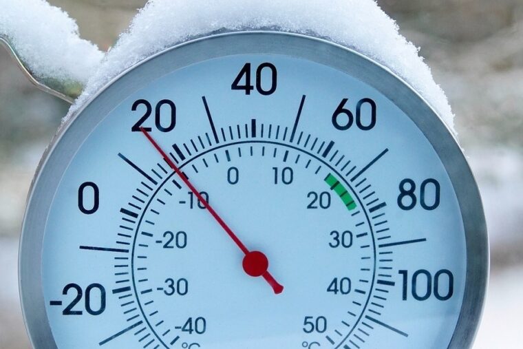 A round thermometer with snow on top displaying 18 degrees Fahrenheit.
