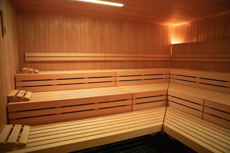 A wooden sauna with three levels of wooden benches and warm lighting.