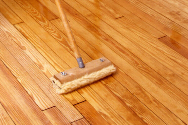 A floor mop applying ZAR® Interior Oil Modified Urethane Sanding Sealer to hardwood floors.