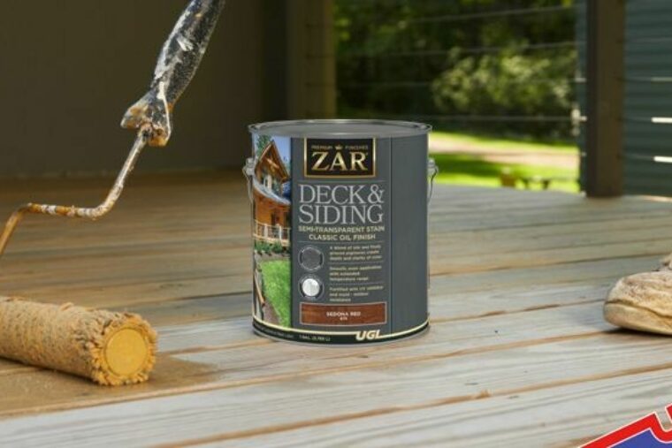 A can of ZAR® stain is sitting on the floor. There is a roller and a person’s sneaker in the image.