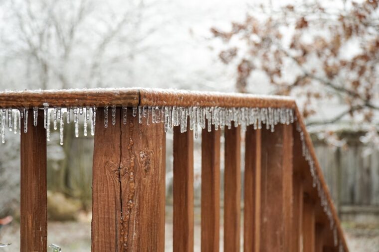 Icicles hanging off a wooden deck railing.