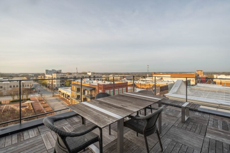 The picture depicts a primarily wooden rooftop overlooking a city.